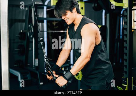 Junger Mann, der Seiltrizeps-Pulldowns durchführt, um Muskeln und Kraft aufzubauen Stockfoto