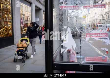 Flyer und Plakate mit den Namen und Gesichtern israelischer Geiseln, die von der Hamas ergriffen wurden, werden am 13. November 2023 an einer Bushaltestelle in London, England, beschädigt, gerissen und verunreinigt. Stockfoto