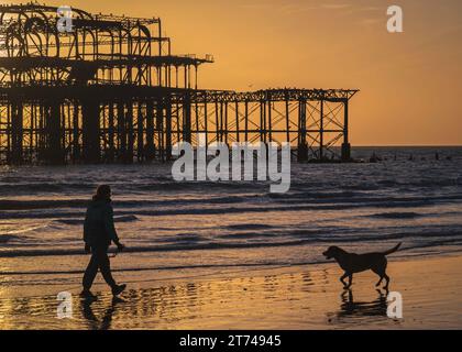 Sonnenuntergang hinter den Ruinen des alten Westpiers an der Küste in Brighton, Sussex, England, Großbritannien Stockfoto