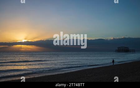 Sonnenuntergang hinter den Ruinen des alten Westpiers an der Küste in Brighton, Sussex, England, Großbritannien Stockfoto