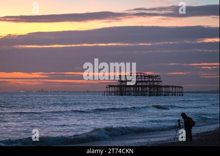 Sonnenuntergang hinter den Ruinen des alten Westpiers an der Küste in Brighton, Sussex, England, Großbritannien Stockfoto