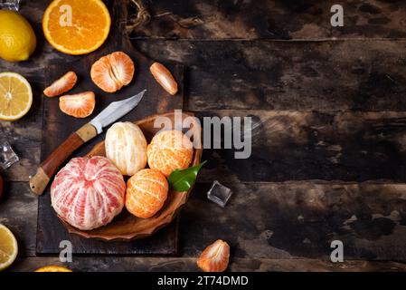 Frische Mandarine, Orange, Zitrone und Grapefruit in einer Schüssel auf einem Holztisch. Mit Eiswürfeln. Draufsicht Stockfoto