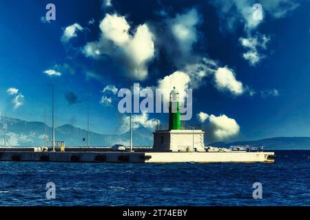 Ein isolierter Leuchtturm steht vor einem hellblauen Himmel mit weißen, flauschigen Wolken Stockfoto