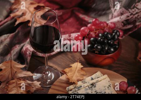 Herbstpicknick mit Wein- und Käseplatte, Früchten und trockenen Blättern Stockfoto