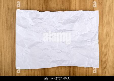 Draufsicht eines zerknitterten weißen Büropapiers auf weißem Hintergrund. Leeres Blatt Papier für Werbung. Kopierbereich. Stockfoto