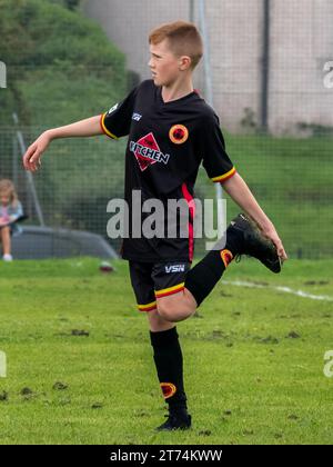 Glasgow, Schottland, Großbritannien, 9. September 2023: Junge Jugendspieler versuchen, nasses Gras von ihren Schuhen zu bekommen. Stockfoto