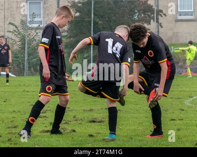 Glasgow, Schottland, Großbritannien, 9. September 2023: Junge Jugendspieler versuchen, nasses Gras von ihren Schuhen zu bekommen. Stockfoto