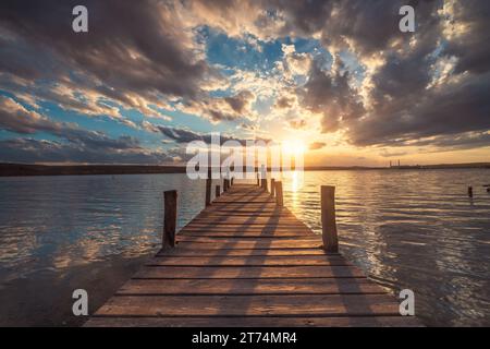 Kleines altes Angeldock am See und malerischer Sonnenuntergang mit dramatischer Wolkenlandschaft über dem Meer Stockfoto