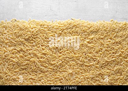 Italienische Pasta Orzo auf hellem Hintergrund, Blick von oben. Nahaufnahme harter Nudeln in Form von Kleinreis. Stockfoto