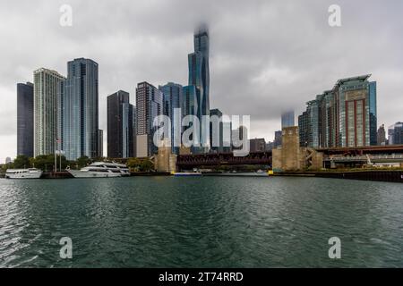 Wolkenkratzer in Chicago am Chicago River berühren die tief hängenden Wolken. Stadtbild des bewölkten Chicago, USA. Die Wolkenkratzer sind Wolkenkratzer Stockfoto