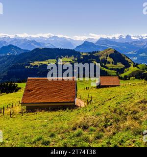 Eine malerische Landschaft mit einer Ansammlung von kleinen, ländlichen Häusern, eingebettet zwischen üppig grünem Gras und der majestätischen Bergkette im Hintergrund Stockfoto