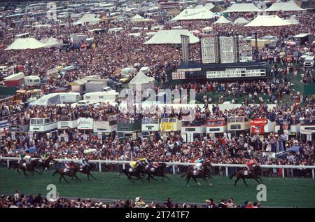Derby Day, Epsom Downs, Derby Pferderennen. Das Pferd, das ins Ziel kommt, die Zuschauermenge „auf dem Hügel“, auf der billigeren, nicht zahlenden Standseite der Rennstrecke. Epsom Downs, Surrey, England. Juni 1985 1980, Großbritannien HOMER SYKES Stockfoto