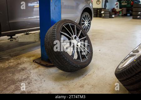 Ein komplettes Rad neigt sich in einer Autowerkstatt gegen eine Säule Stockfoto