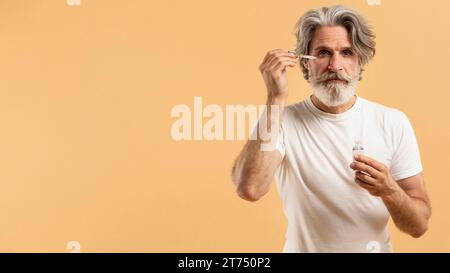 Ein hochrangiger bärtiger Mann, der Serum aufträgt Stockfoto