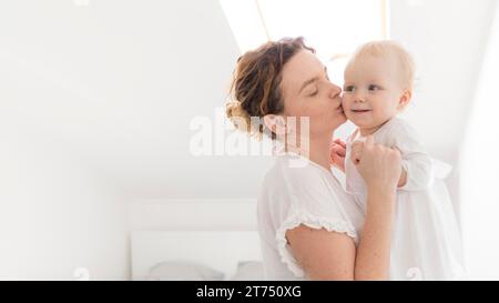 Schöne Mutter küsst Baby Mädchen Stockfoto