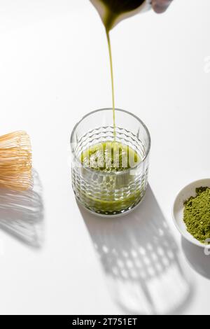 Schließen Sie den Matcha-Tee, und gießen Sie ihn ins Glas Stockfoto