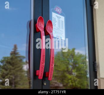 CASS LAKE, MN - 3. JUN 2023: Türgriffe für die Milchküche mit Queen in Form von roten Plastiklöffeln. Stockfoto