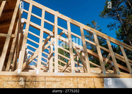 Holzsparren auf einer neuen Baustelle an einem sonnigen Tag mit blauem Himmel. Stockfoto