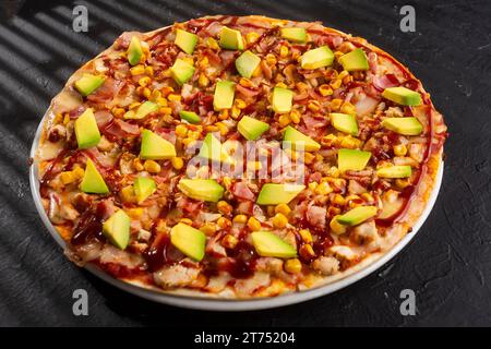 Holzkohle-Hähnchenpizza mit BBQ-Sauce - Speck, Mais, Avocado und neapolitanische Sauce Stockfoto