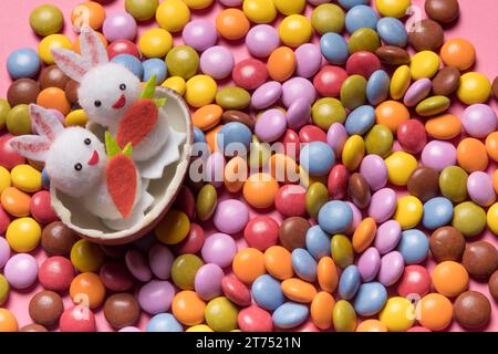 Niedliche zwei Häschen in gebrochenen ostereiern, bunten Edelsteinbonbons Stockfoto