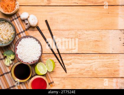 Erhöhte Aussicht Pilzsprossen Bohnen Reis Brokkoli Zitronensauce mit Essstäbchen vor dem Holztisch Stockfoto