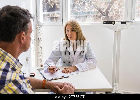 Die Ärztin sagt ihrem Patienten die Diagnose in ihrer Arztpraxis Stockfoto