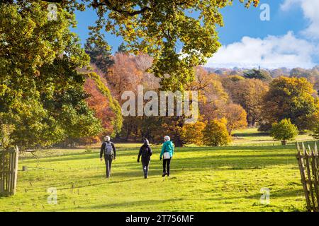 Menschen, die in der Herbstsonne in Chirk North Wales durch das Gelände und die Parkanlage des National Trust Chirk Castle gehen Stockfoto