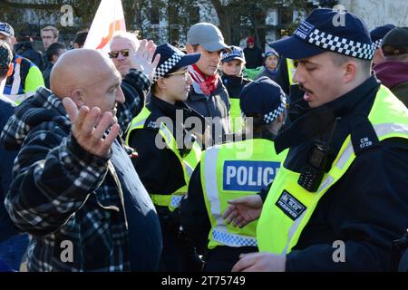 Met Polizeibeamte befragen und durchsuchen Gegendemonstratoren vor Beginn des pro-palästinensischen marsches am Tag des Waffenstillstands 11. November 2023. Stockfoto