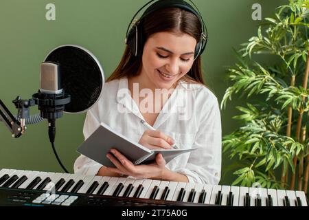 Smiley-Musikerin mit Klaviertastatur, die während der Aufnahme Lieder schreibt Stockfoto