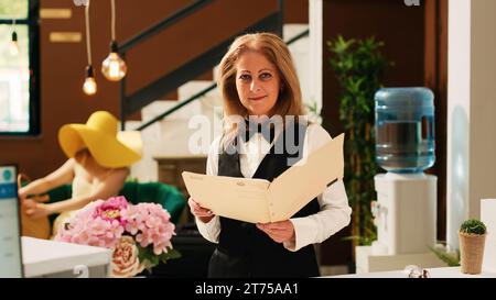 Der Concierge des Hotels überprüft Buchungen oder Reservierungen und hilft Reisenden an der Rezeption in der Lobby beim Check-in. Rezeptionist an der Rezeption, tropisches exotisches Resort. Stockfoto