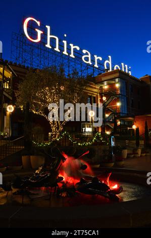 Das Schild über dem Ghirardelli Square in San Francisco wird in der Abenddämmerung beleuchtet, ebenso wie der Wasserbrunnen auf dem plaza Stockfoto