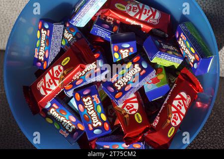 Süßigkeiten in einer Plastikschale zum verteilen. Nestle Mini Smarties Schokoladenpunkte mit einer Süßigkeitenschale und KitKat Schokoladenriegel. Stockfoto