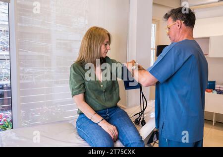 Ein männlicher Arzt bringt ein Blutdruckmessgerät an seinen Patienten im Krankenhaus. Stockfoto