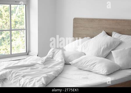 Helles Schlafzimmer mit komfortablem Doppelbett und weißen Kissen Stockfoto