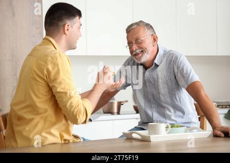 Junger Mann, der seinen Vater in der Küche ernährt Stockfoto