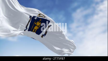 Massachusetts Bundesflagge winkt im Wind mit der nationalen amerikanischen Flagge an einem klaren Tag. 3D-Darstellung. Geriffeltes Material. Selektiver Fokus Stockfoto