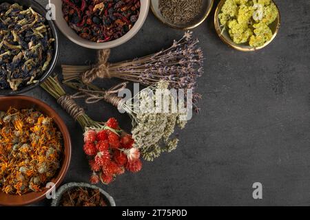 Viele verschiedene trockene Kräuter und Blumen auf dunkelgrauem Tisch, flach gelegen. Leerzeichen für Text Stockfoto