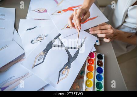 Eine gesichtslose Frau zeichnet Aquarelle von Sportbekleidung. Nahaufnahme der Hände eines Modedesigners. Stockfoto