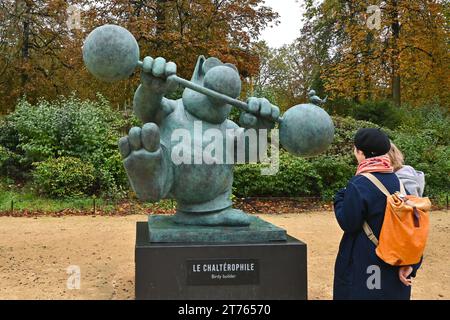 Menschen, die Le Chat Skulptur „Le Chaltérophile“ (Birdy Builder) von Philippe Geluck im Brüsseler Park (Parc de Bruxelles) betrachten – Brüssel, Belgien Stockfoto