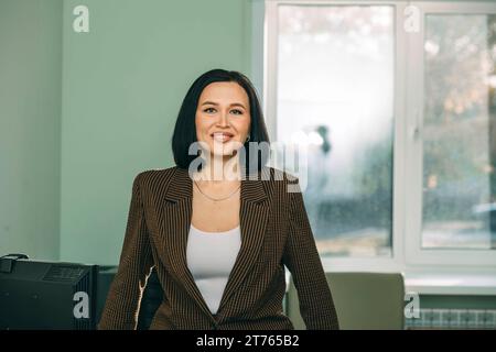 Junge glückliche Geschäftsfrau mit Computer im modernen Büro. Stilvoller, schöner Manager, der an Finanz- und Marketingprojekten arbeitet Stockfoto