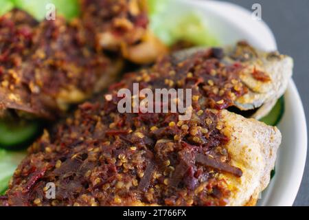 Ikan Goreng Masak Sambal, gebratener Fisch mit Chilipaste. Traditionelles indonesisches und malaysisches Gericht. Nahaufnahme Stockfoto