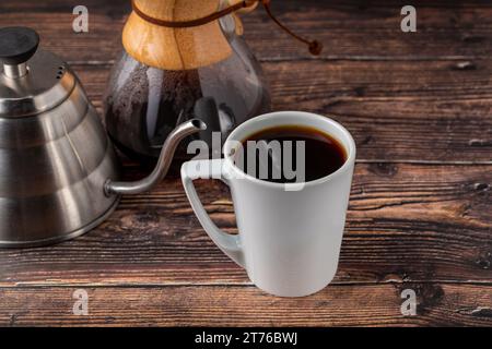 Eine Tasse Kaffee und die dritte Generation gießen über die Kaffeemaschine auf dem Steinboden Stockfoto