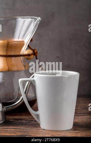 Eine Tasse Kaffee und die dritte Generation gießen über die Kaffeemaschine auf dem Steinboden Stockfoto