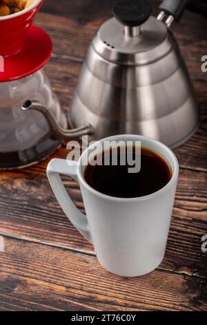 Eine Tasse Kaffee und die dritte Generation gießen über die Kaffeemaschine auf dem Steinboden Stockfoto