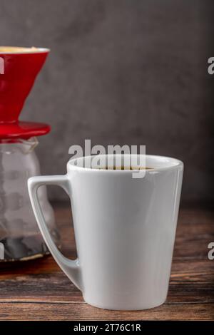 Eine Tasse Kaffee und die dritte Generation gießen über die Kaffeemaschine auf dem Steinboden Stockfoto