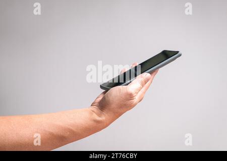 Mann Hand hält ein Telefon, Seitenansicht. Ein unweißer Hintergrund, Kopierraum. Stockfoto