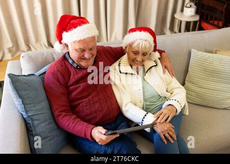 Glückliches kaukasisches Seniorenpaar, das zu Hause ein Video-Gespräch über ein weihnachtsvideo mit Tablet hat Stockfoto