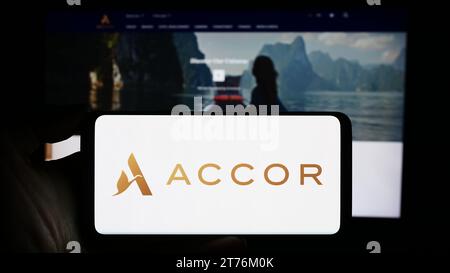Person mit Smartphone und Logo des französischen Hotelunternehmens Accor S.A. vor der Website. Schwerpunkt auf dem Display des Telefons. Stockfoto