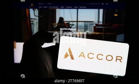Person, die ein Mobiltelefon mit dem Logo des französischen Hotelunternehmens Accor S.A. vor der Webseite hält. Schwerpunkt auf dem Display des Telefons. Stockfoto