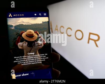 Person mit Mobiltelefon und Webseite des französischen Hotelunternehmens Accor S.A. vor dem Firmenlogo. Konzentrieren Sie sich auf die Mitte des Telefondisplays. Stockfoto